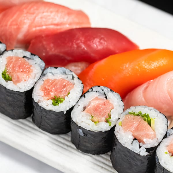 Close-up of Kakui Sushi's tuna maki rolls and various nigiri sushi on a white plate.