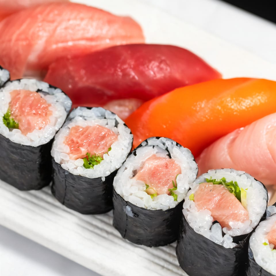 Close-up of Kakui Sushi's tuna maki rolls and various nigiri sushi on a white plate.