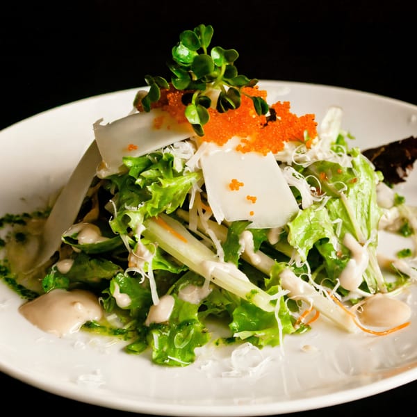 Fresh green salad with white fish, orange tobiko, and microgreens, drizzled with dressing.