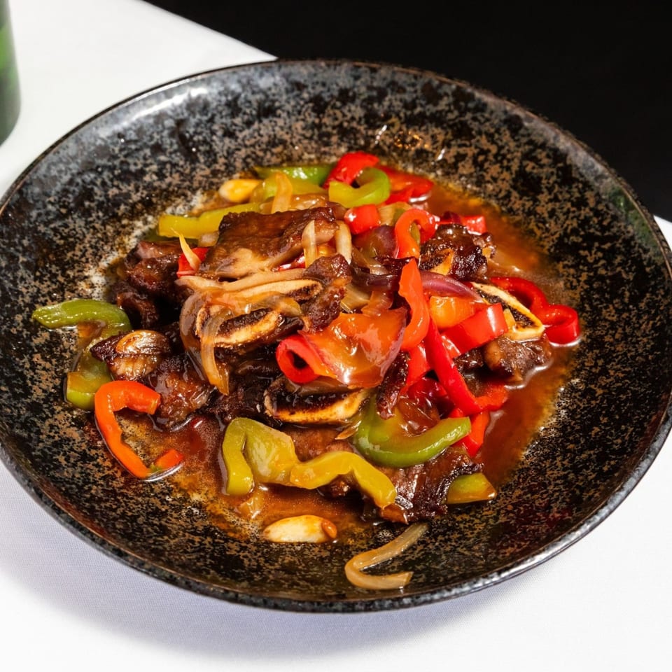 Kakui Sushi's beef short ribs with red and green bell peppers, onions, and garlic in a dark sauce.
